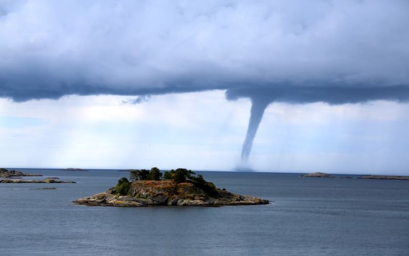 Natural Disaster Waterspout Tornado approaching Island and mainland in daytime..