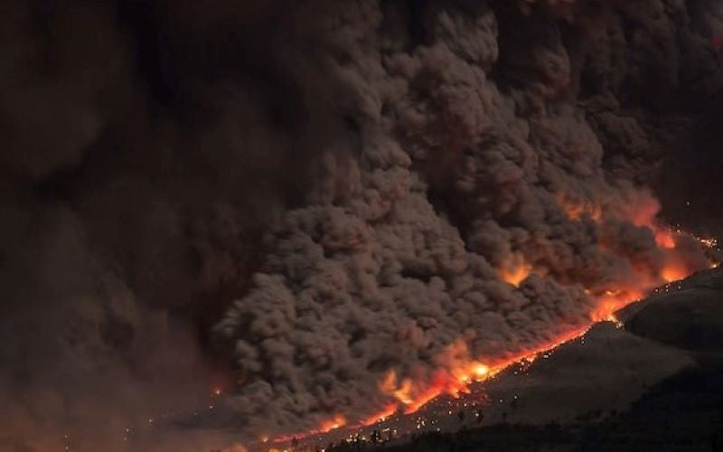 Natural Disaster Volcanic devastation. Orange hot lava flows over valley town with thick smoke and ash at night. 