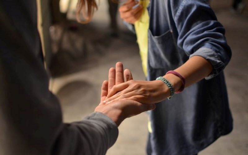 Shows community volunteers reaching out to clasp hands. Working together.